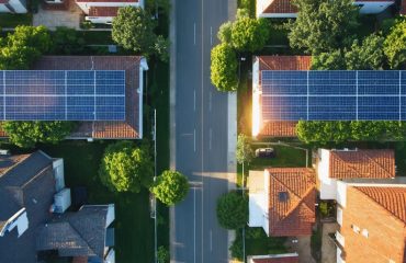 An illustration of a residential neighborhood with solar panels under daylight and dusk conditions, depicting energy storage, smart grid integration, and balanced power distribution.