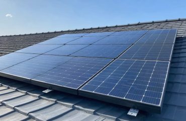 Brightly lit residential rooftop featuring three solar panels connected in series, demonstrating the concept of increased voltage and power generation for efficient energy conversion.