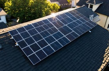 Aerial view of a neighborhood with modern rooftop solar panels and a shadow symbolizing vandalism threats, highlighting the importance of solar-specific insurance coverage.