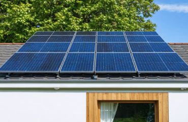 A modern house featuring solar water heating panels on its roof, illuminated by sunlight, symbolizing energy efficiency and sustainable living.