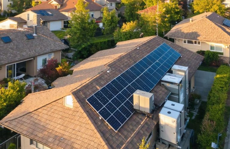 "Aerial view of neighborhood homes equipped with solar panels and battery storage, representing a community microgrid with a focus on sustainable energy."