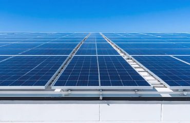 "School rooftop with solar panels under clear blue skies showcasing renewable energy adoption."