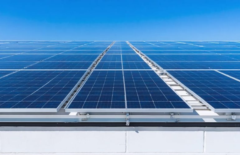 "School rooftop with solar panels under clear blue skies showcasing renewable energy adoption."
