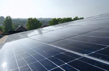 "Clean and efficient solar panel installation on a rooftop under diffuse sunlight, with suburban landscape in the background."